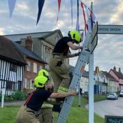 Nevertheless, bunting is continuing to go up in areas of Suffolk. Pictured: Fire crews helping put up bunting in Debenham.